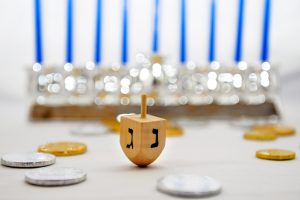 Photo of a dreidel (spinning top), gelts (candy coins) and a silver menorah for Hanukkah, isolated on white